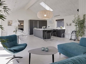 Una cocina moderna con una isla central, taburetes de bar y un área de comedor con mesa y sillas.