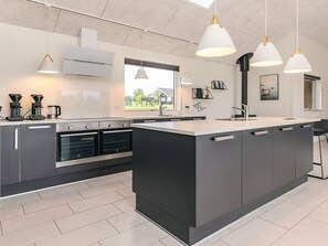 Una cocina moderna con una isla central, hornos empotrados e iluminación colgante.
