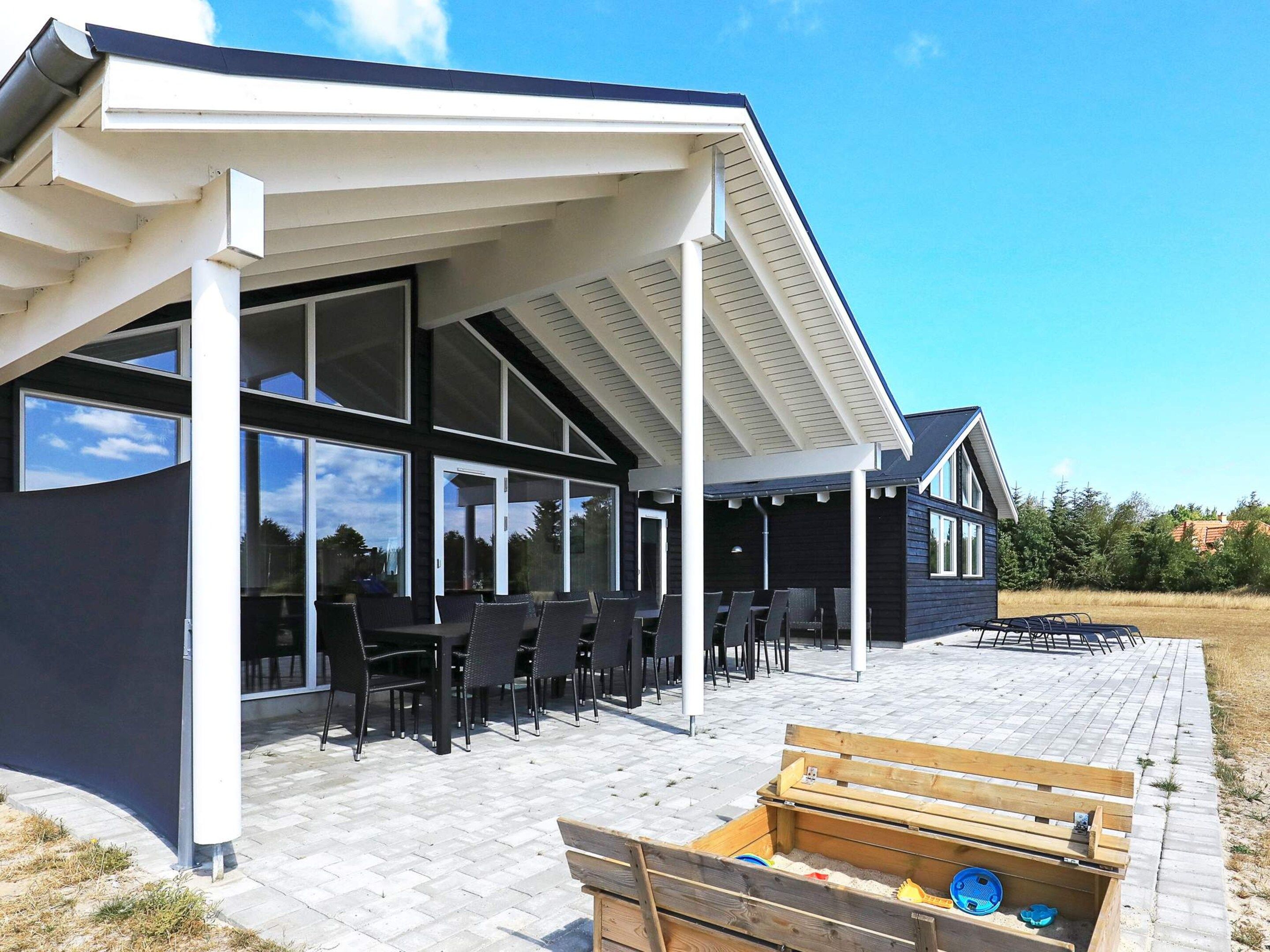 A modern house with a covered patio, large windows, and outdoor furniture.