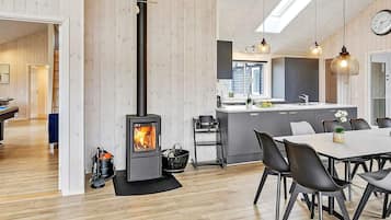 Et moderne køkken med en central ø, et spiseområde med stole og en brændeovn.