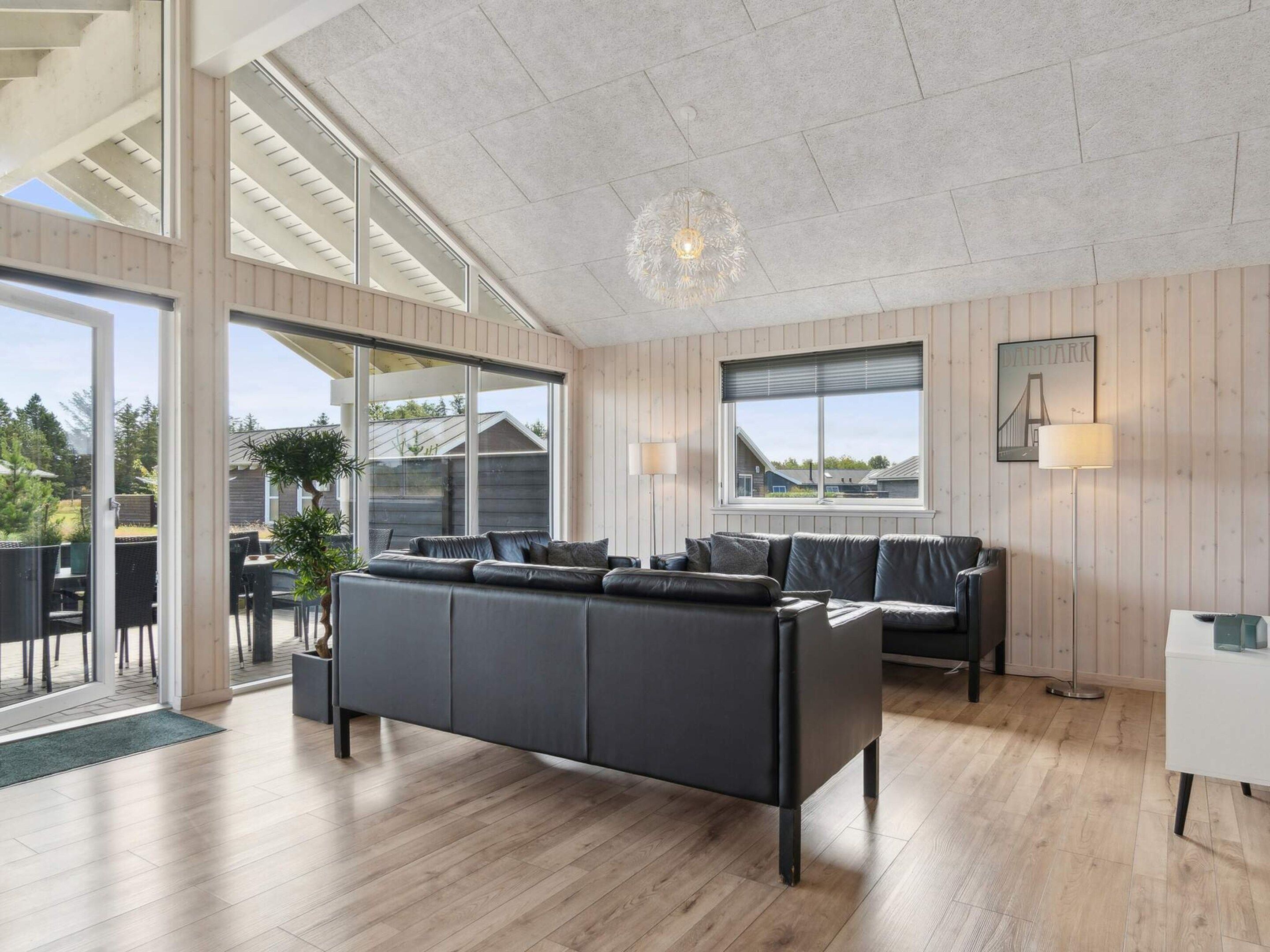 A modern living room with a large sofa, a dining area with chairs, and a view of the outside.