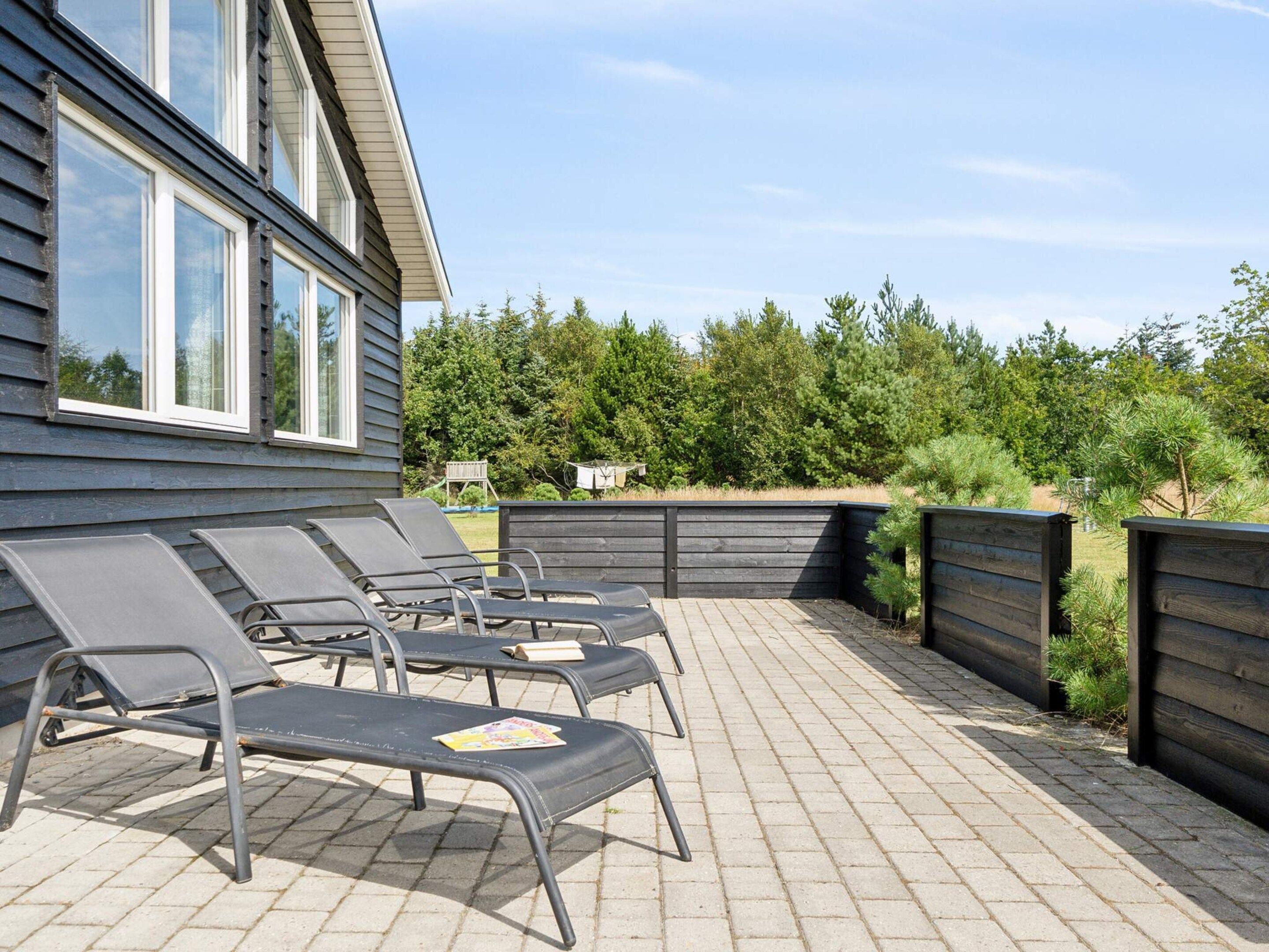 En terrasse med udendørs møbler og et træhegn.
