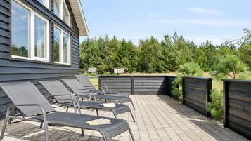 En terrasse med udendørs møbler og et træhegn.