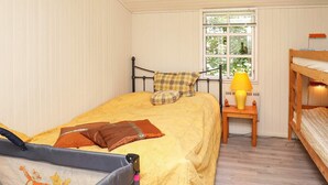 Habitación acogedora con una cama individual, una ventana con vistas a zonas verdes, una mesita con una lámpara y una litera a la derecha.
