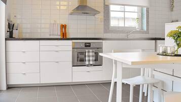A modern kitchen with white cabinetry, a built-in oven, and a window above the sink.