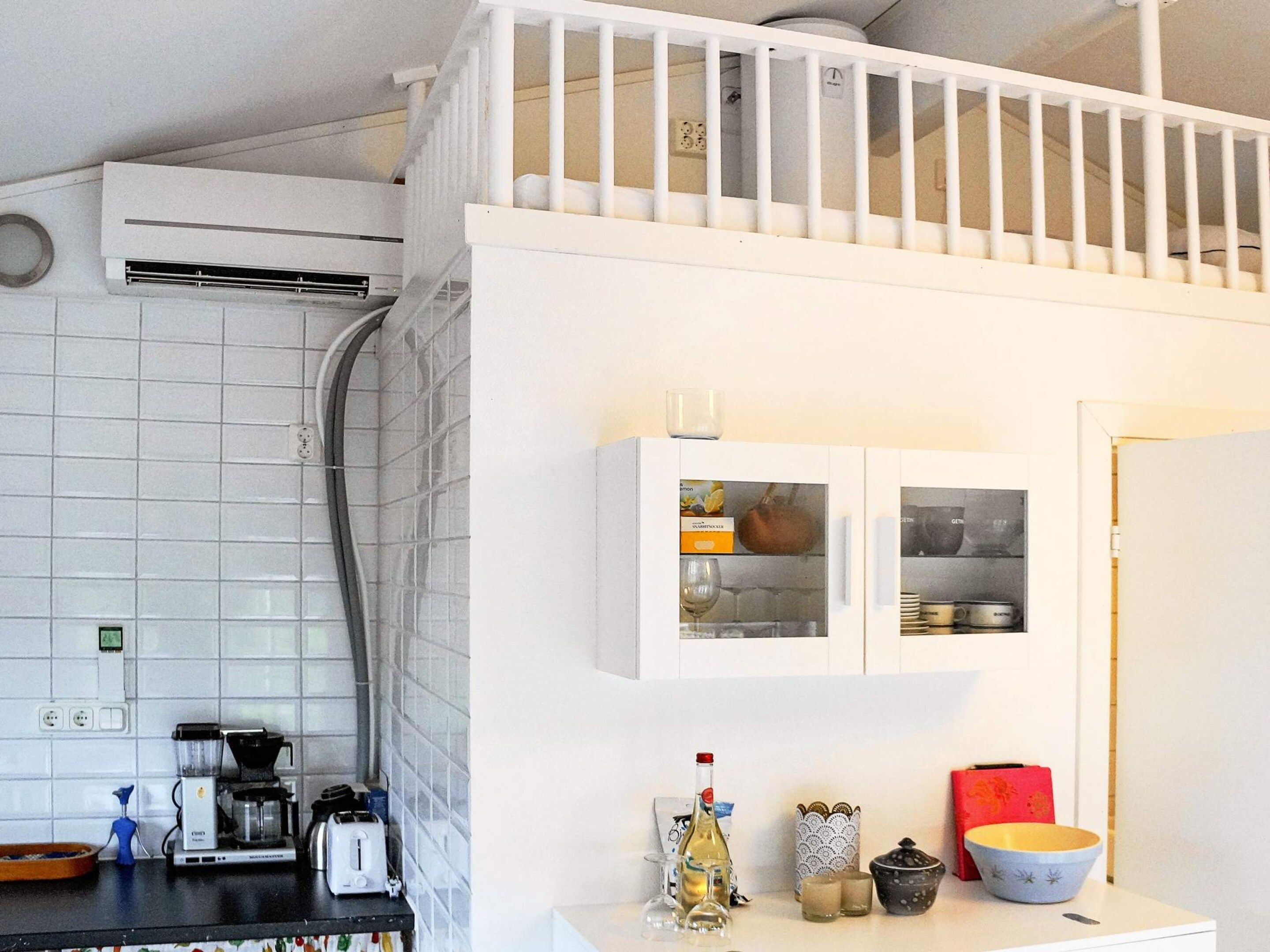 A kitchen with a white countertop, a coffee maker, a toaster, and a wine bottle.