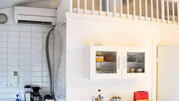 A kitchen with a white countertop, a coffee maker, a toaster, and a wine bottle.