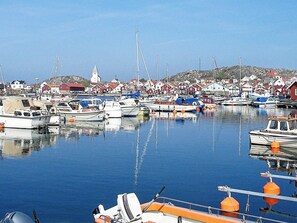A marina with various boats docked, surrounded by houses with red roofs.