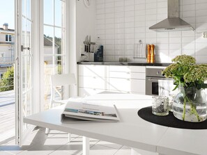 A modern kitchen with white cabinets, a stainless steel range hood, and a dining area with a table and chairs. - 4 Person Holiday Home in Skarhamn (Skaerhamn)