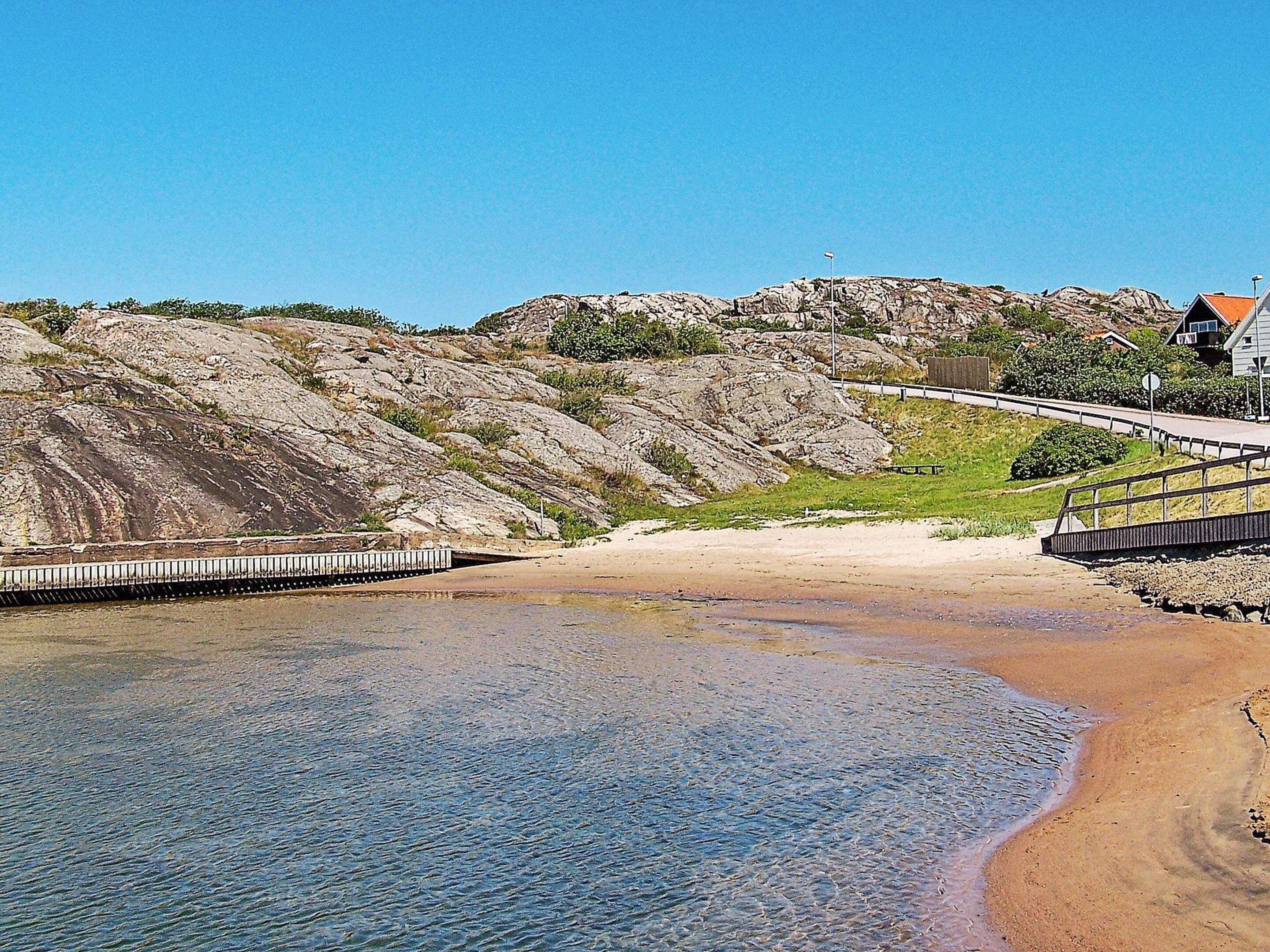 Un paisaje costero con una colina rocosa, una playa de arena y un edificio con techo rojo.