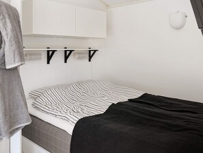 A compact bedroom with a bed, a towel, a white cabinet, and a wall-mounted light fixture. - 4 Person Holiday Home in Skarhamn (Skaerhamn)