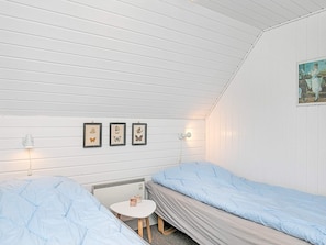 A room with two beds, a small table, a wall-mounted heater, and framed butterfly pictures. - Tranquil Holiday Home in Ringkøbing near Sea (Ringkobing)