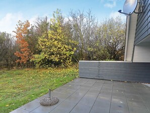 A patio with a round table, a satellite dish, and a tree with yellow leaves.