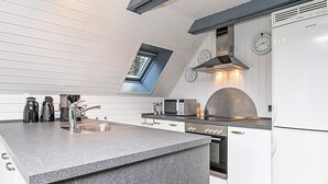 Une cuisine moderne dotée d’un îlot central, d’un four encastré et d’une horloge murale.