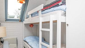 Une chambre avec un lit superposé, une fenêtre, un radiateur et une lampe.