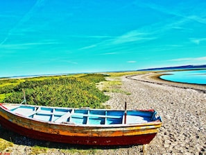 A boat on a pebbly shore with a lake and forest in the background. - Tranquil Holiday Home in Ringkøbing near Sea (Ringkobing)
