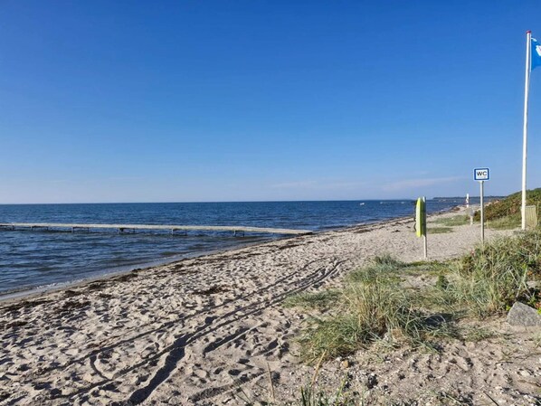 A beach with a wooden jetty, a sandy shore, and a WC sign. - 4 Star Holiday Home in Bogense (Bogense)