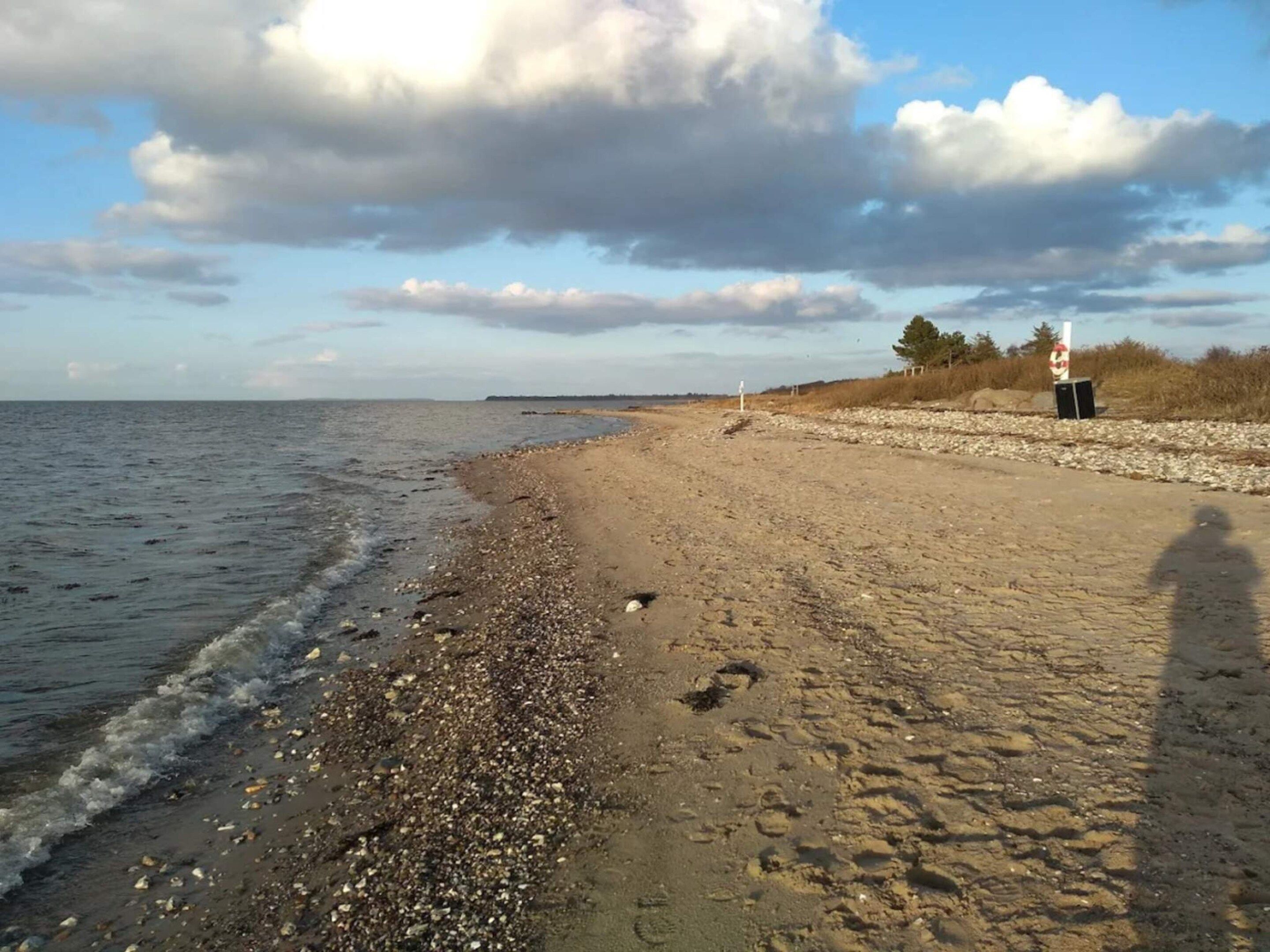 A beach with pebbles, a clear sky, and a distant horizon.