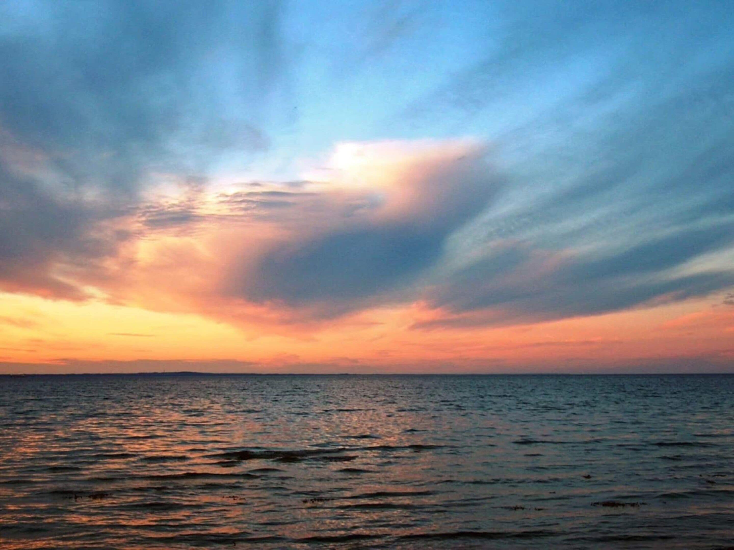 A sunset over a body of water with a clear horizon.