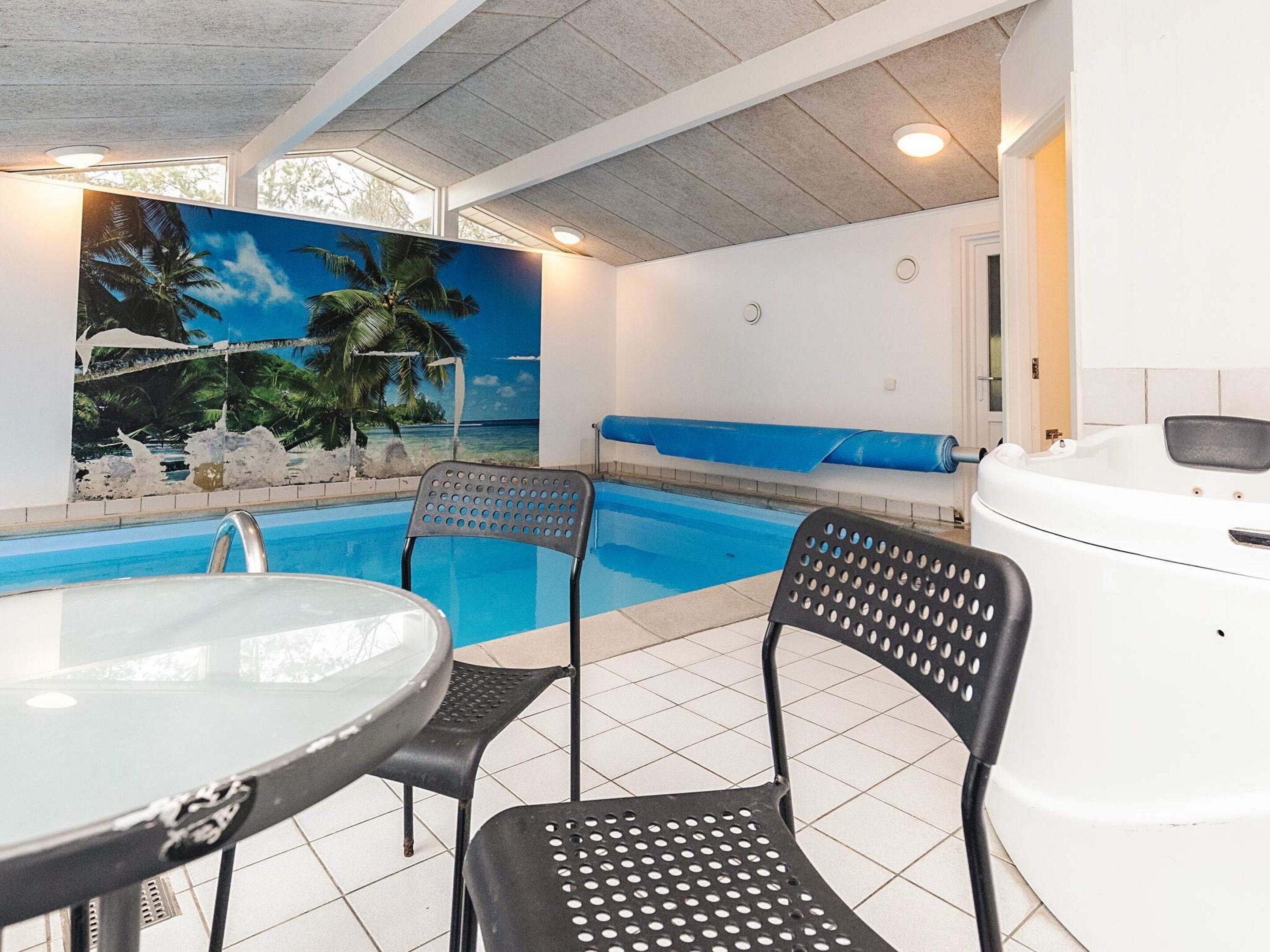 Un espace piscine avec vue sur les palmiers et la mer, un jacuzzi et deux chaises longues.