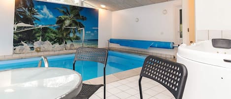 Un espace piscine avec vue sur les palmiers et la mer, un jacuzzi et deux chaises longues.