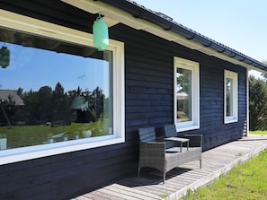 A dark wooden building with large windows and a green lantern hanging above. - 5 Star Holiday Home in Vaeggerlose (Vaeggerlose)
