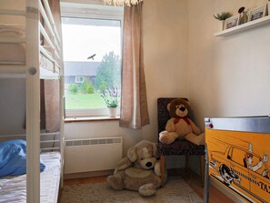 Et værelse med køjeseng, et vindue med gardiner, en bamse, en hund og et skab formet som en taxa.