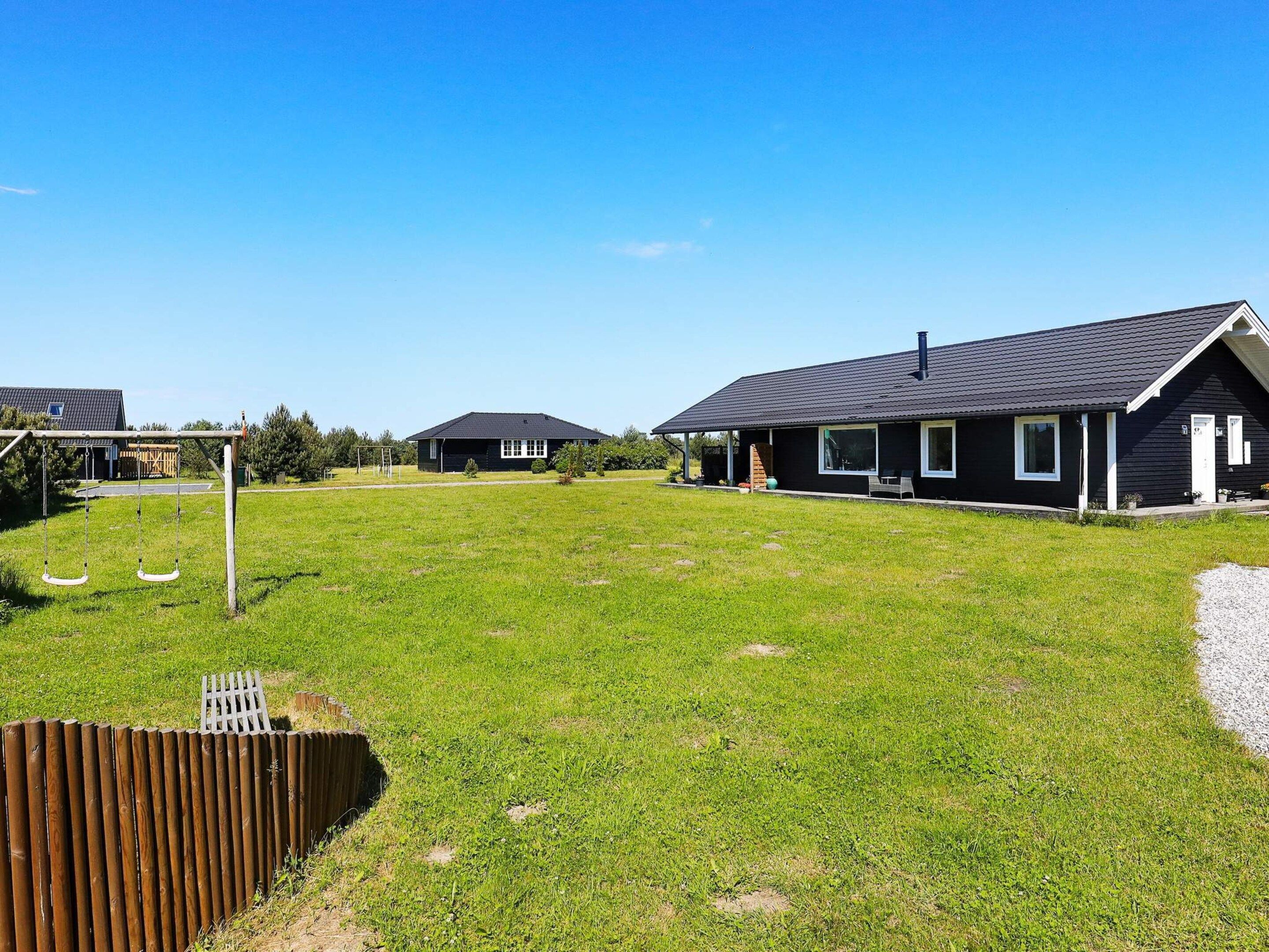 A residential area with houses, a swing set, and a fenced yard.