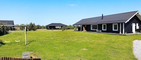 A residential area with houses, a swing set, and a fenced yard.