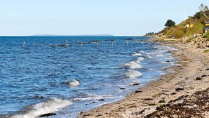 A beach with a rocky shoreline, waves, and a distant shoreline. - 6 Person Holiday Home in Brenderup Fyn-by Traum (Middelfart)