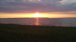 A sunset over a body of water with a distant shoreline.