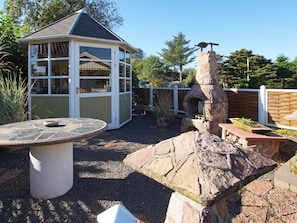 A patio area with a stone table, a small shed, and a stone-built outdoor oven.