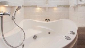 Una bañera blanca con ducha, panel de control y desagüe.