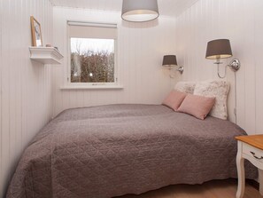 A bedroom with a bed, a window, a wall-mounted lamp, and a bedside table. - 5 Star Holiday Home in Hemmet (Hemmet)