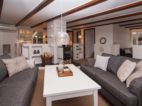 A modern living room with a white coffee table, grey sofas, and a fireplace.