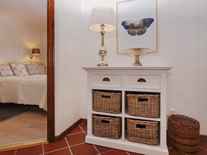 A hallway with a white console table, wicker baskets, a lamp, and a framed butterfly artwork. - 5 Star Holiday Home in Hemmet (Hemmet)