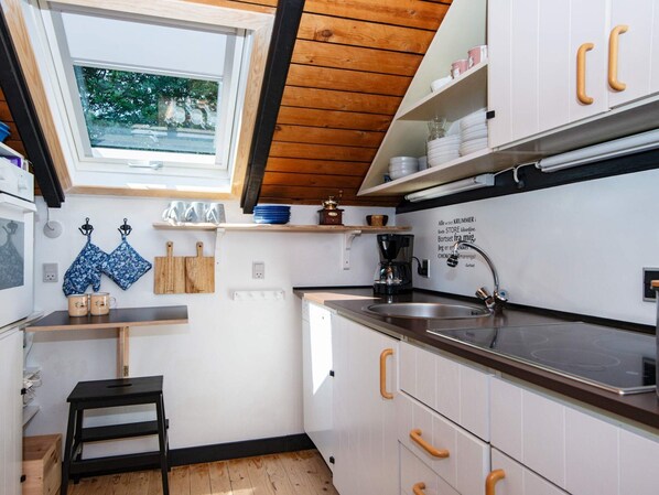A compact kitchen with white cabinets, a black countertop, and a window above the sink. - 4 Person Holiday Home in Oksbol (Oksbol)