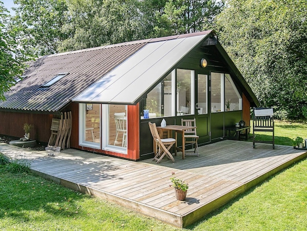 A small, single-story cabin with a sloped metal roof, large windows, and a wooden deck.