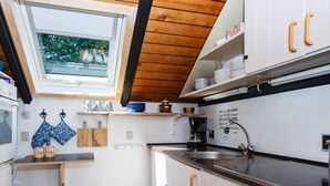 A compact kitchen with white cabinets, a black countertop, and a window above the sink. - 4 Person Holiday Home in Oksbol (Oksbol)
