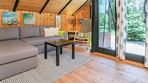 A cozy cabin interior with a wooden ceiling, a sofa, a table, and a chair. - 4 Person Holiday Home in Oksbol (Oksbol)