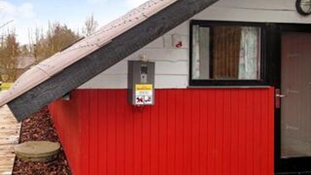 A building with a red exterior, a black door, and a small window. - 4 Person Holiday Home in Oksbol (Oksbol)