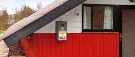 Un bâtiment à l’extérieur rouge, avec une porte noire et une petite fenêtre.
