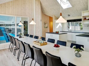 A modern kitchen with a dining area, a large window overlooking a pool, and pendant lighting. - Chic Holiday Home in Hovedstaden near Sea (Vejby)