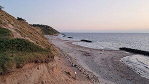 A coastal landscape with a sandy beach, rocky outcrops, and a grassy hillside. - Chic Holiday Home in Hovedstaden near Sea (Vejby)