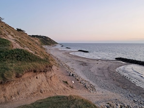 A coastal landscape with a sandy beach, rocky outcrops, and a grassy hillside. - Chic Holiday Home in Hovedstaden near Sea (Vejby)