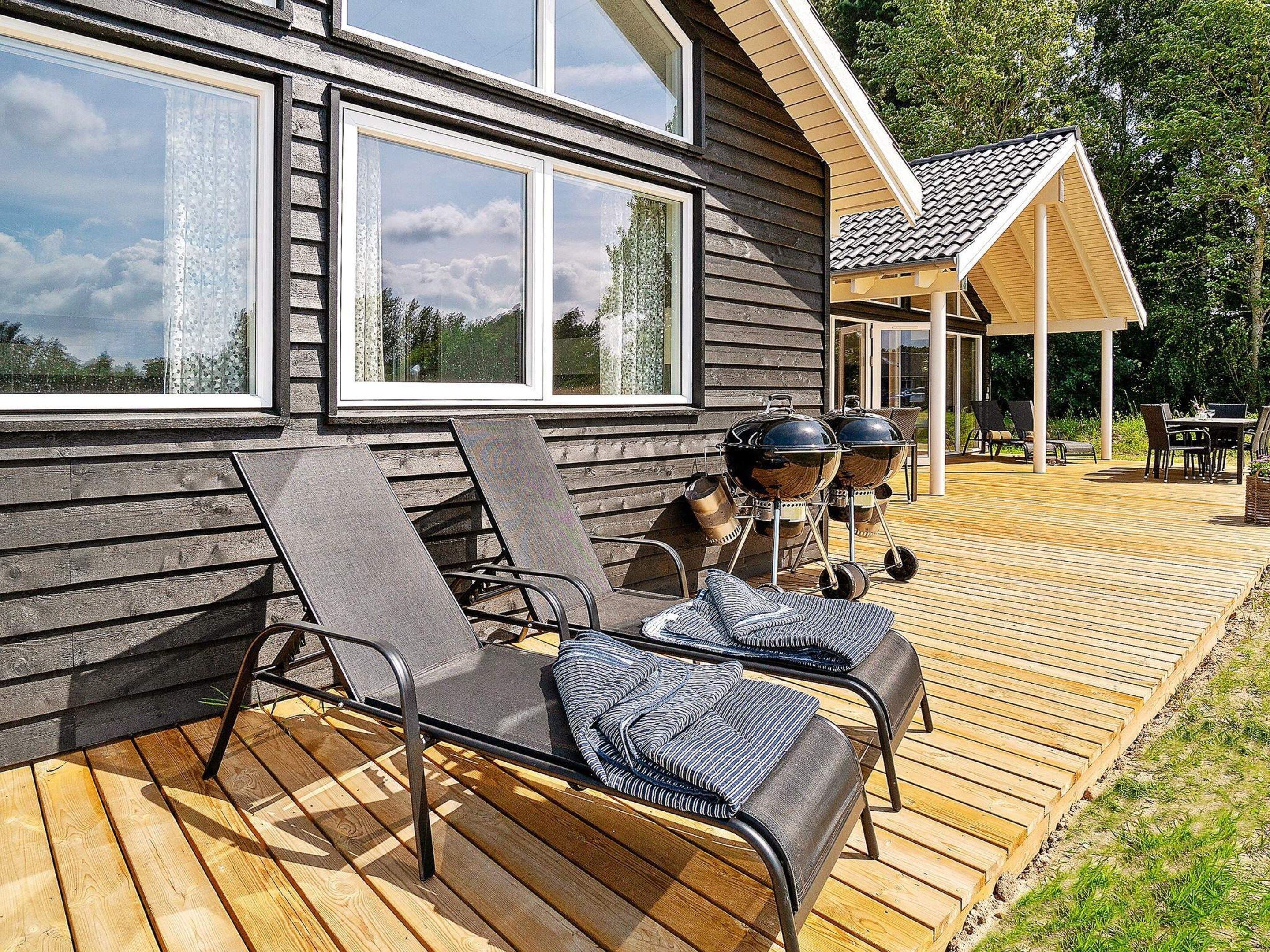 A wooden deck with lounge chairs and a barbecue grill.