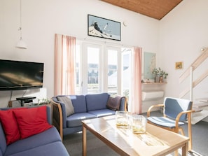 A living room with a sofa, a coffee table, a TV, and a staircase. - 5 Person Holiday Home in Vestervig-by Traum (Vestervig)