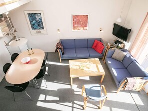 A living room with a blue sofa, a coffee table, a TV, and artwork on the walls. - 5 Person Holiday Home in Vestervig-by Traum (Vestervig)