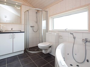 Une salle de bain moderne équipée d’une douche, de toilettes et d’une baignoire, avec une grande fenêtre et un lambris en bois.