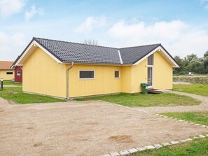 Un bâtiment jaune avec un toit gris, une petite fenêtre et une porte.